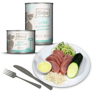 Mjamjam Hundenassfutter Pute mit Reis und Zucchini, Dosen und angerichtete Portion auf Teller.