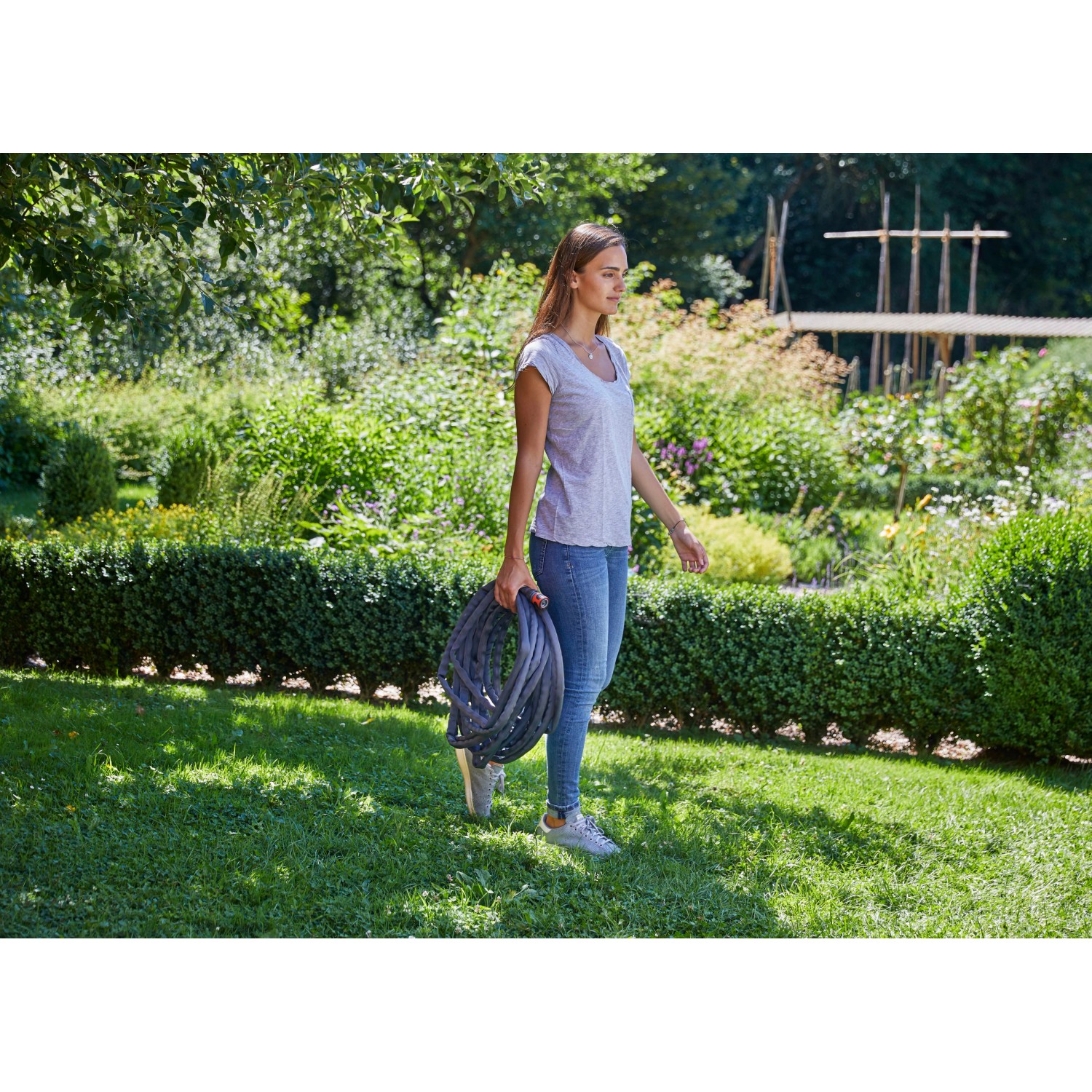 Frau trägt Gardena Textilschlauch-Set Liano™ 15 m im Garten.