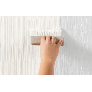 Alpina Effekt-Kamm in Nutzung: Hand zieht Kamm über weiße, strukturierte Wandfarbe.