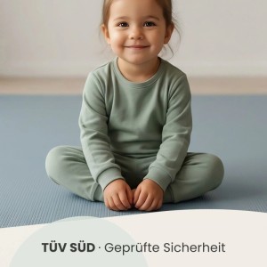 Kind sitzt auf LittleTom Spiel- & Krabbelmatte Puzzlematte in Grau-Blau. Weiche, isolierende Unterlage.