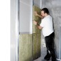 Ein Mann montiert Rockwool Sonorock Trennwandplatten (40mm) aus Steinwolle in einer Wand.