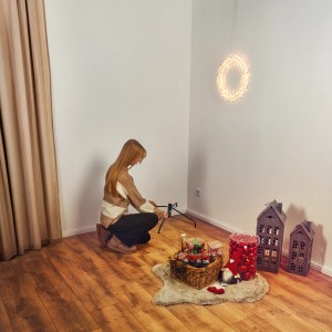 Frau montiert Kreuzständer für künstliche Tanne Blavand 150cm, mit Deko im Wohnzimmer.