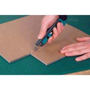 Wolfcraft Abbrechklingenmesser 18 mm schneidet Karton auf grüner Schneidematte.