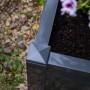 Quadratischer, anthrazitfarbener KHW Pflanzkasten mit Erde und Blumen.