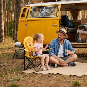 Mädchen sitzt im gelben Sunula Kinder Campingstuhl mit Löwenmotiv neben Vater vor Campingbus.