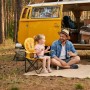 Mädchen sitzt im gelben Sunula Kinder Campingstuhl mit Löwenmotiv neben Vater vor Campingbus.