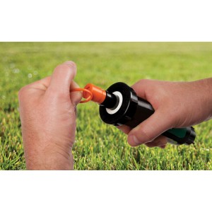 Rain Bird Profi-Versenksprüher IG 13 mm (1/2) ohne Düse in der Hand, vor Rasenfläche.