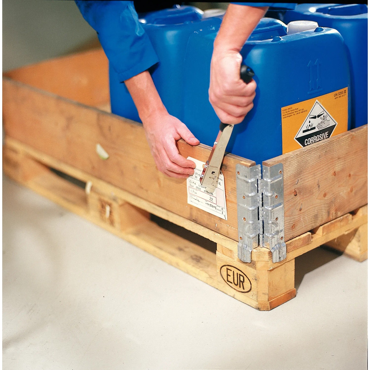 Rapid Hammertacker R19 im Einsatz: Anbringen eines Etiketts an einer Palette mit blauen Kanistern.