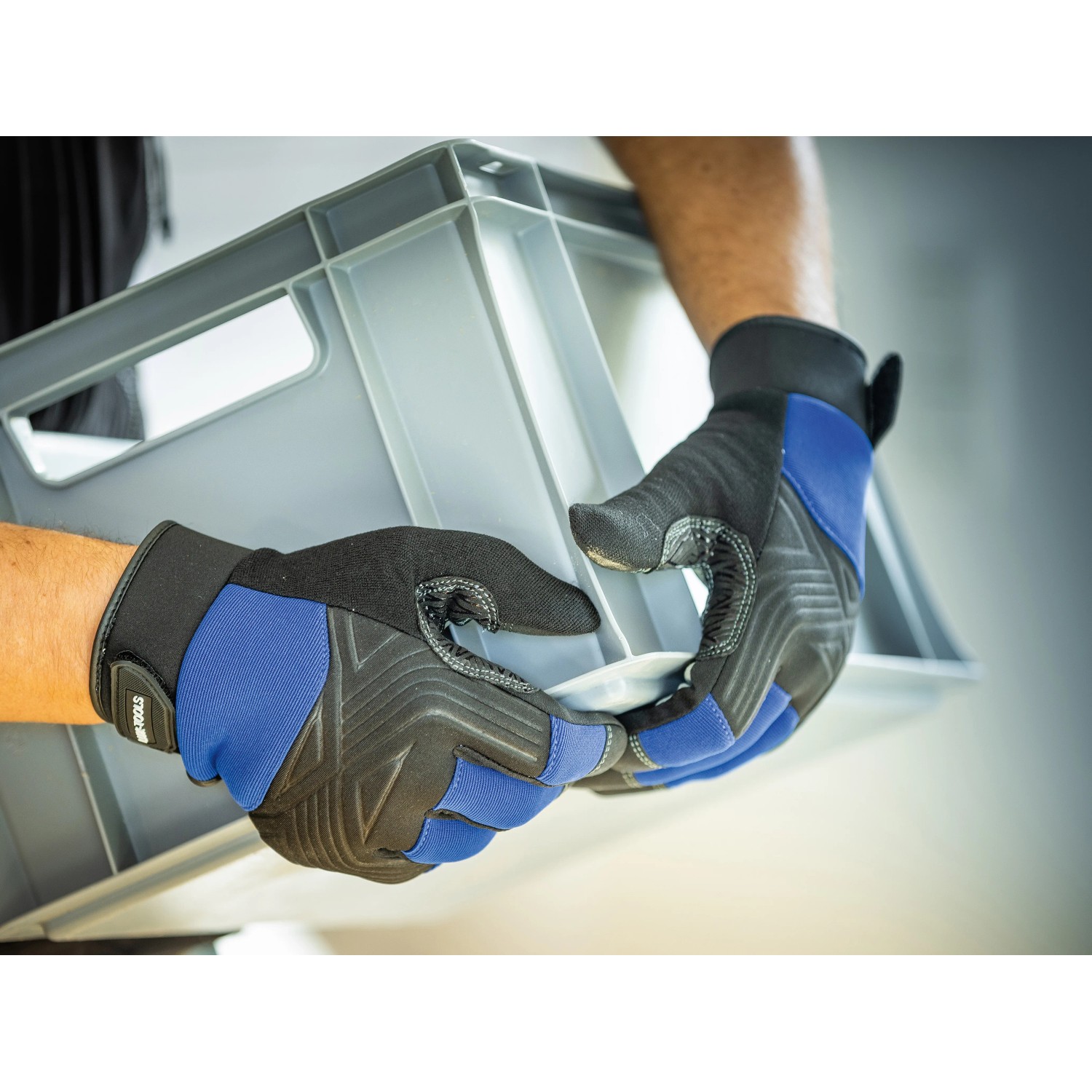 Hände mit LUX Arbeitshandschuhen Tough Gr. 9 halten graue Kiste.