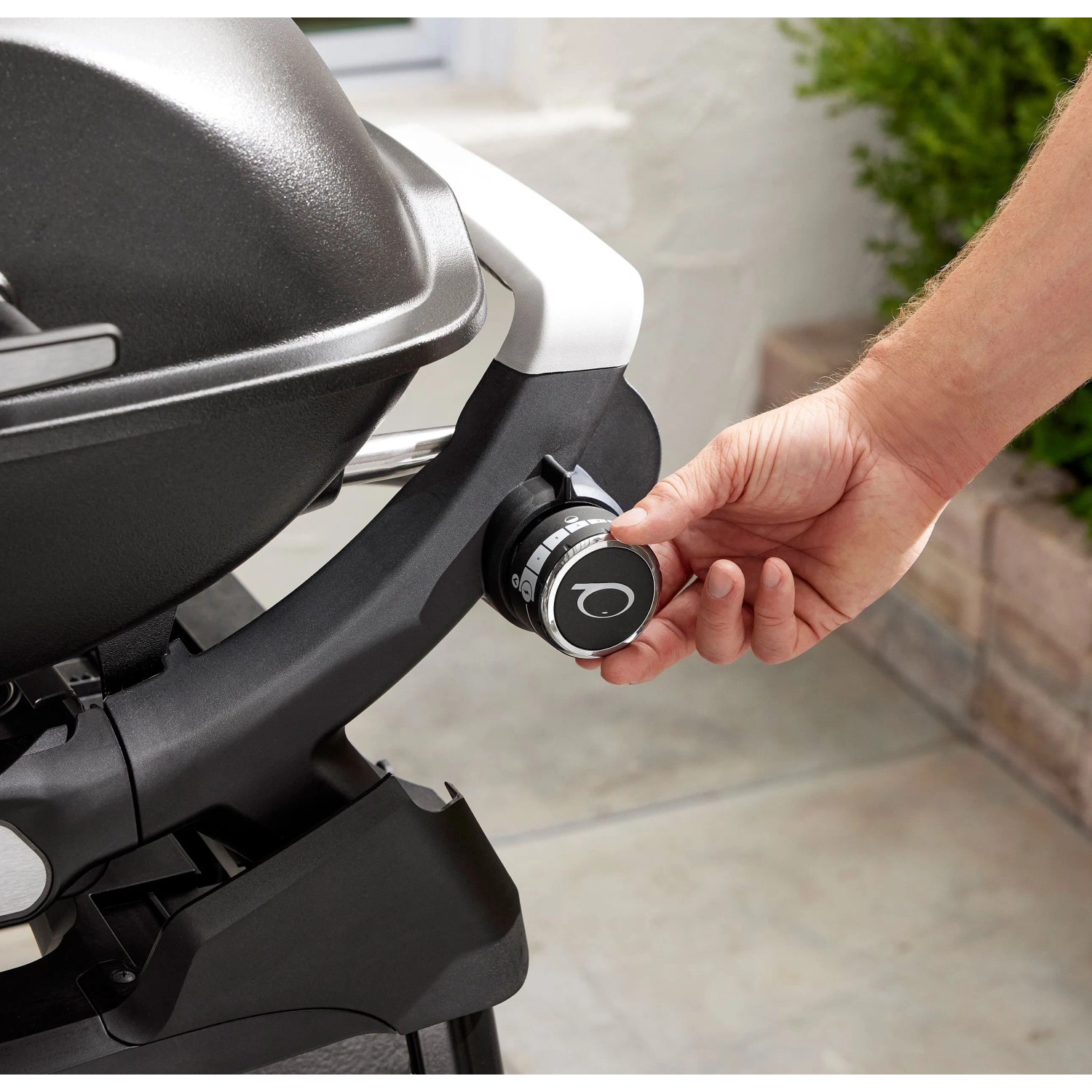Detailaufnahme: Weber Gasgrill Q2200N, Hand reguliert Temperatur am schwarzen Grill.