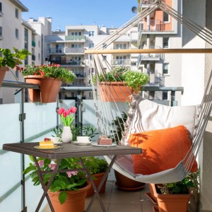 Schwarzer klappbarer Gartentisch in Holzoptik auf einem Balkon, mit Kaffee und Kuchen gedeckt. Perfekt für kleine Außenbereiche.