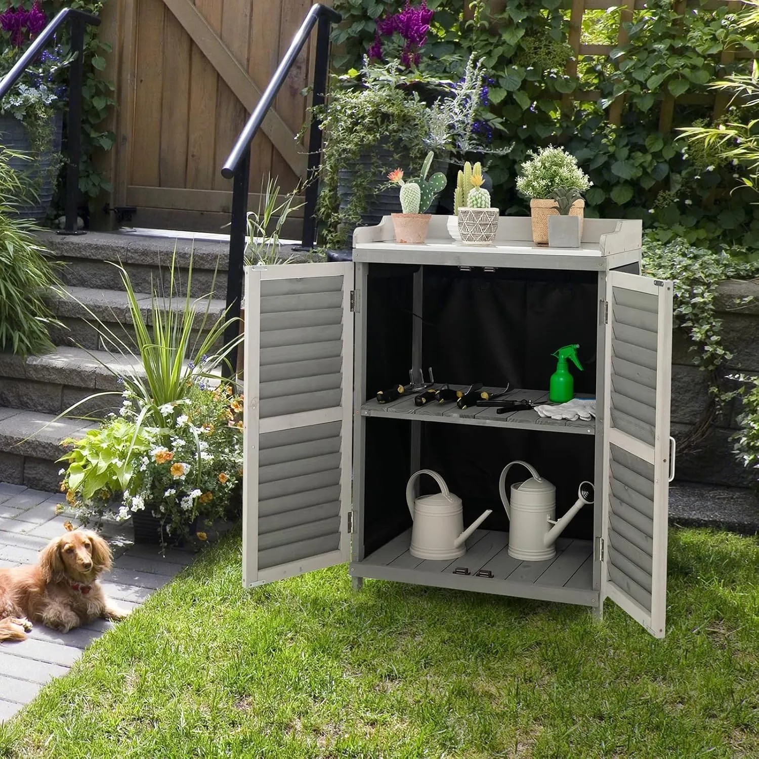 Grauer Costway Gartenschrank aus Holz mit geöffneten Türen und Gartenwerkzeug im Hintergrund.