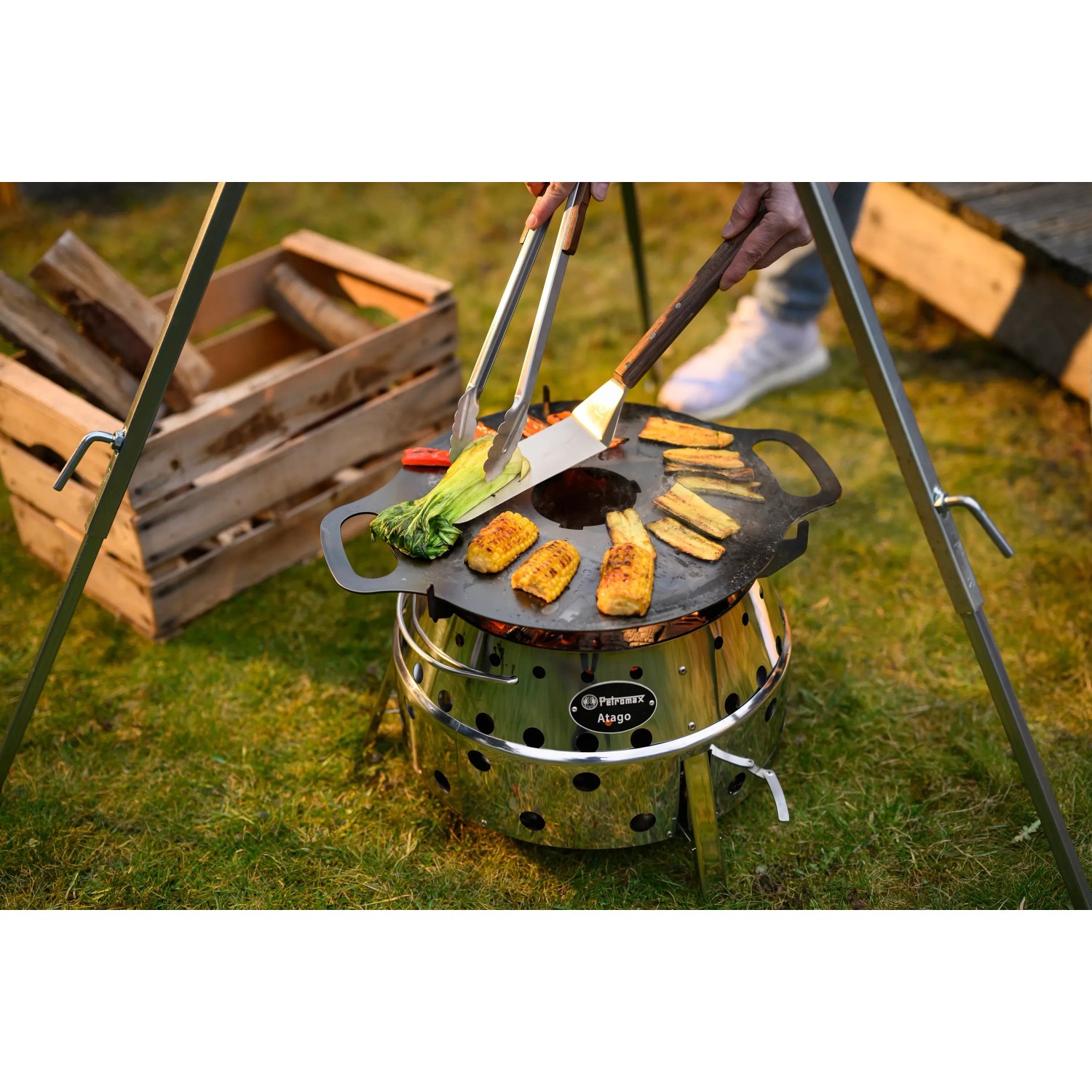 Petromax Atago Grill-Set SK40: Kompakter Gasgrill mit Grillspießen und Speisen auf dem Grill.