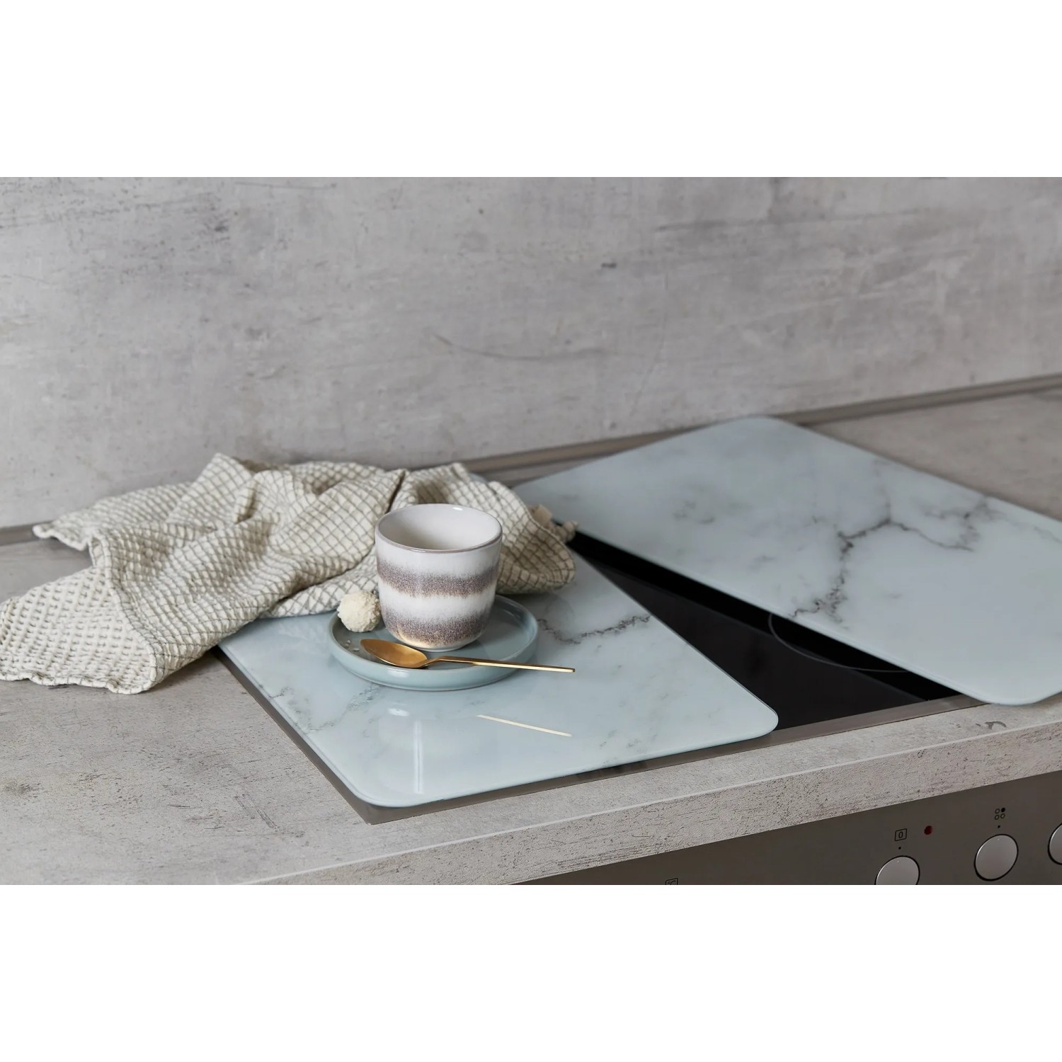 Wenko Herdabdeckplatten Marmor 2er Set auf Herd mit Tasse und Geschirr.