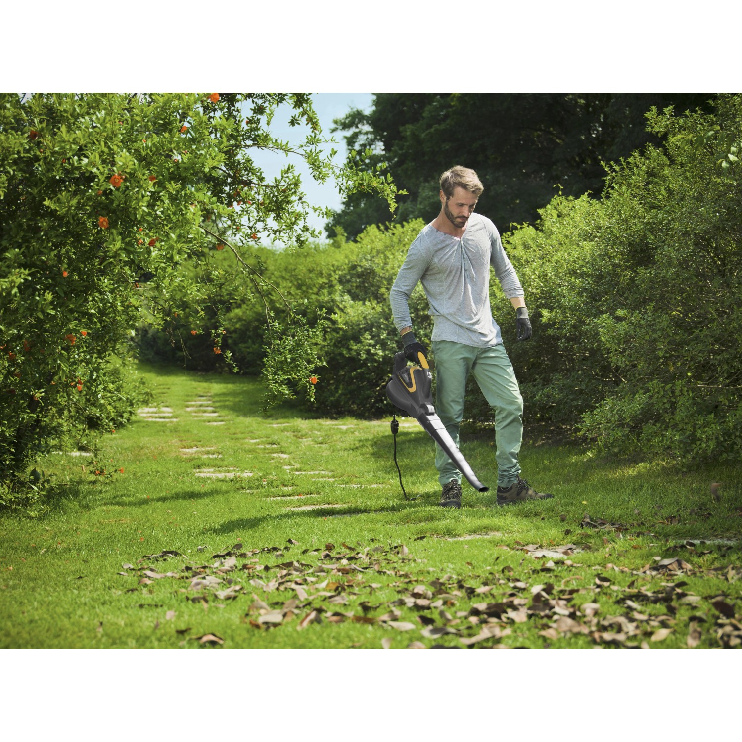 Mann nutzt Stiga Elektro-Laubbläser BL 130c V im Garten, um Laub zu entfernen.