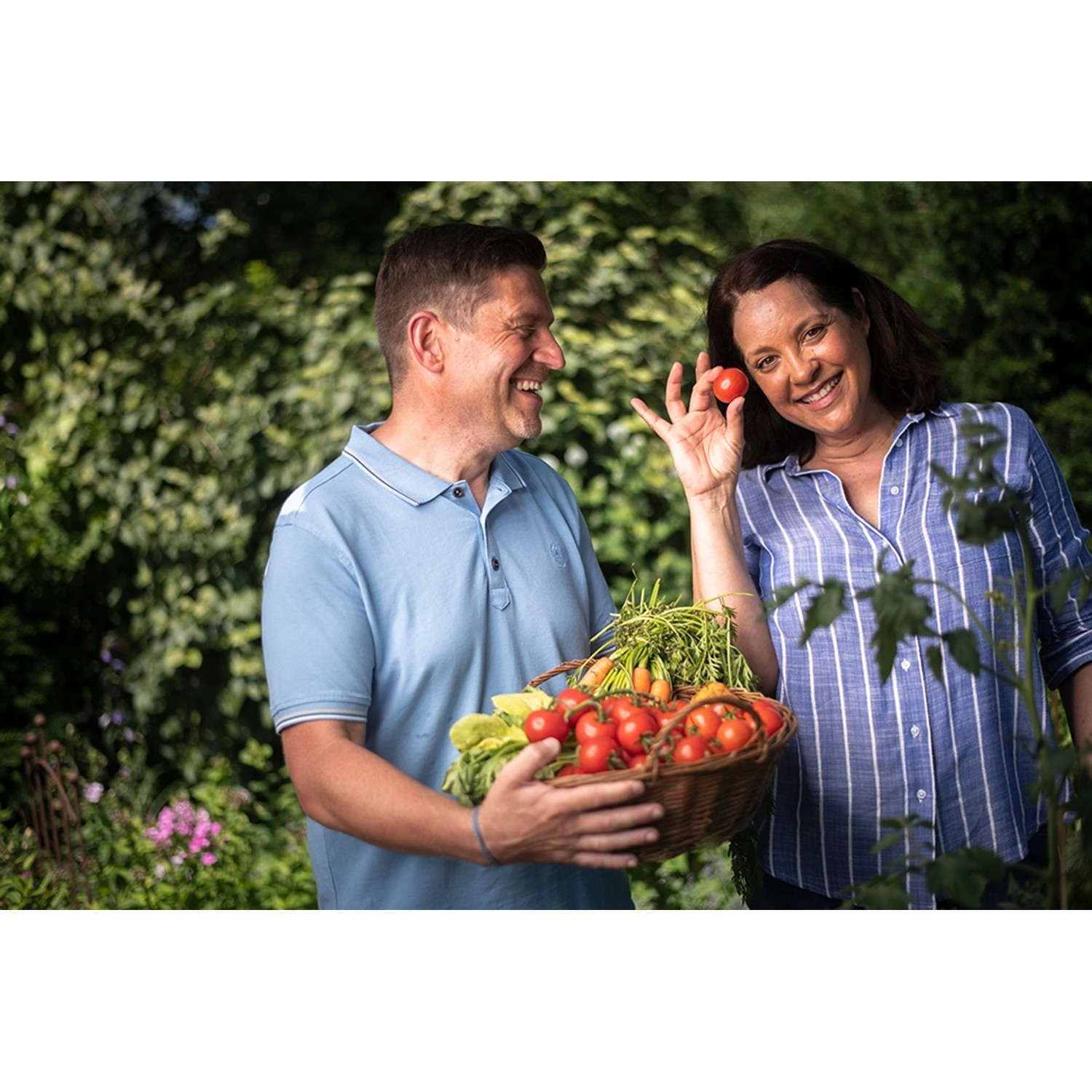 Glückliches Paar mit Gemüseernte aus Floragard Bio-Erde im Garten.