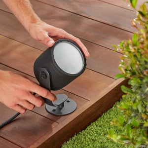 Schwarze Philips Hue Lily XL LED-Gartenleuchte wird auf Holzterrasse montiert.