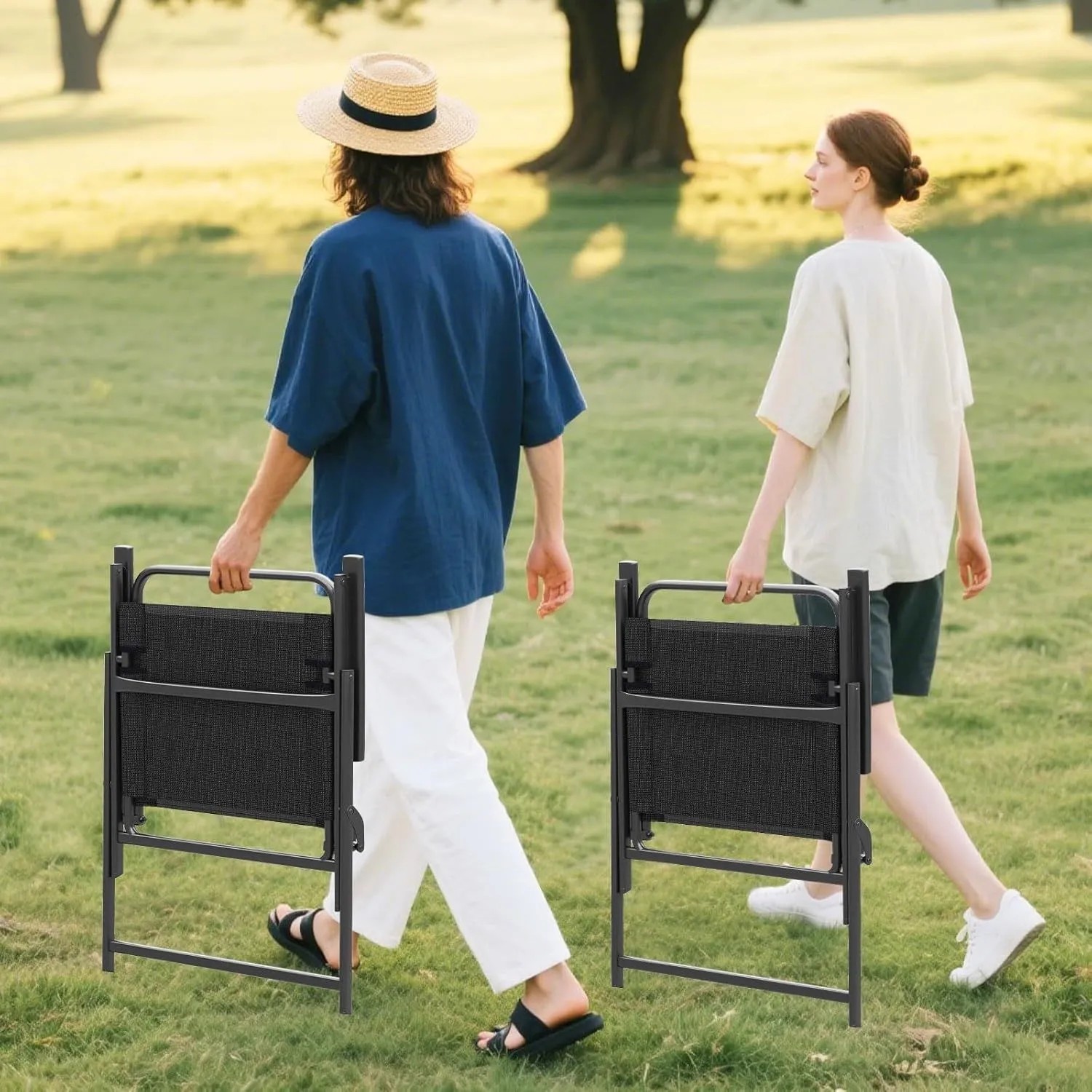 Zwei Personen tragen zusammengeklappte, schwarze Costway Gartenstühle mit Armlehnen.