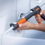 OBI Kartuschenpresse in Anwendung: Handwerker dichtet Fuge im Bad mit Silikon ab.