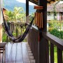 Braunes Bambus Windspiel im Tempel-Design hängt auf Holzveranda. Dekorative Figur für Garten, Balkon, Terrasse.