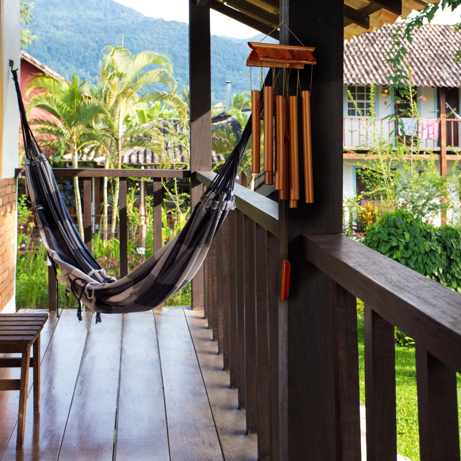 Braunes Bambus Windspiel im Tempel-Design hängt auf Holzveranda. Dekorative Figur für Garten, Balkon, Terrasse.