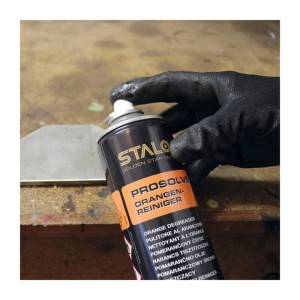 Hand mit Handschuh sprüht STALOC Orangenreiniger auf Metall. Reinigungsmittel für Fettentfernung auf Oberflächen.