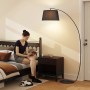 Schwarze HOMCOM Stehlampe mit Stoffschirm, Bogenleuchte im Wohnzimmer mit lesender Person.