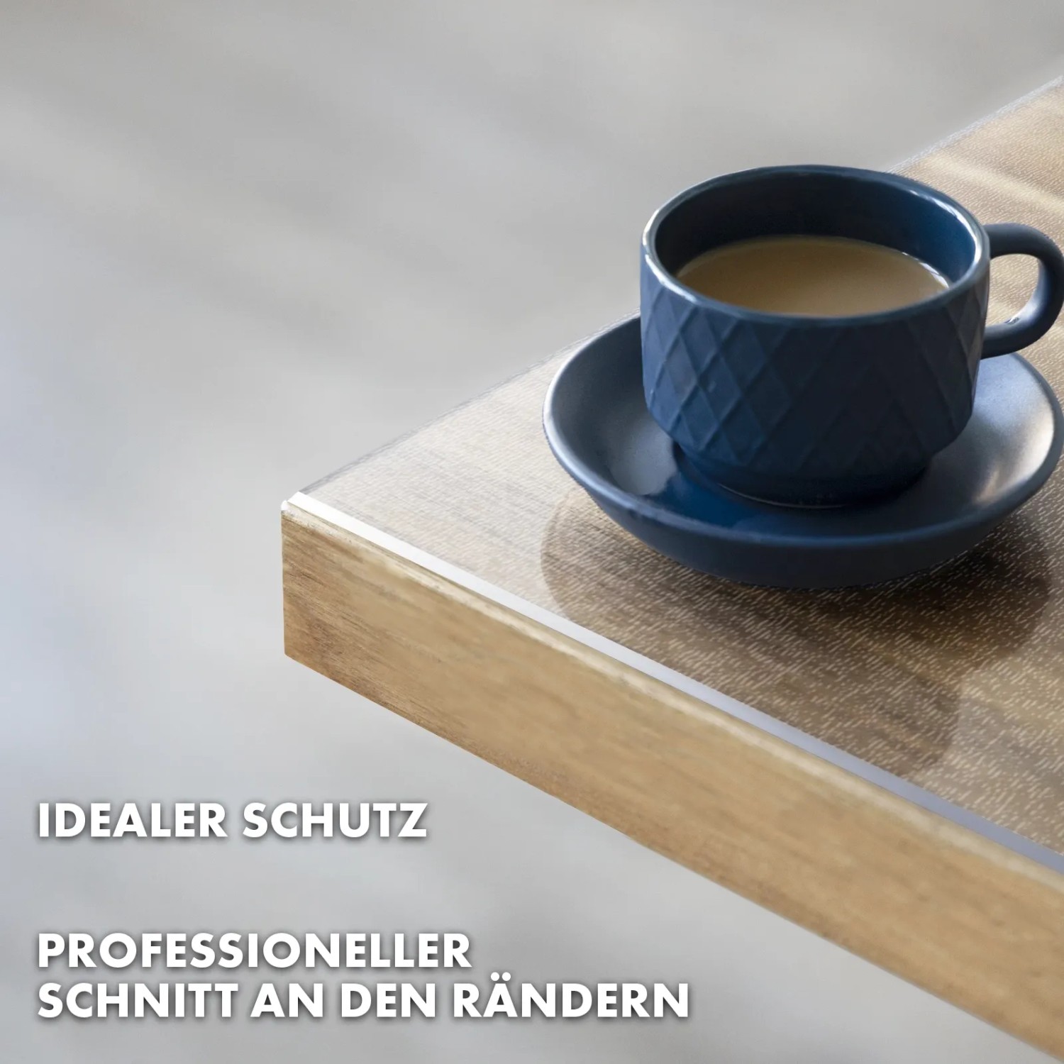 Mattierte, transparente KARAT Tischfolie Imperial mit abgeschrägter Kante und blauer Tasse auf Holztisch.