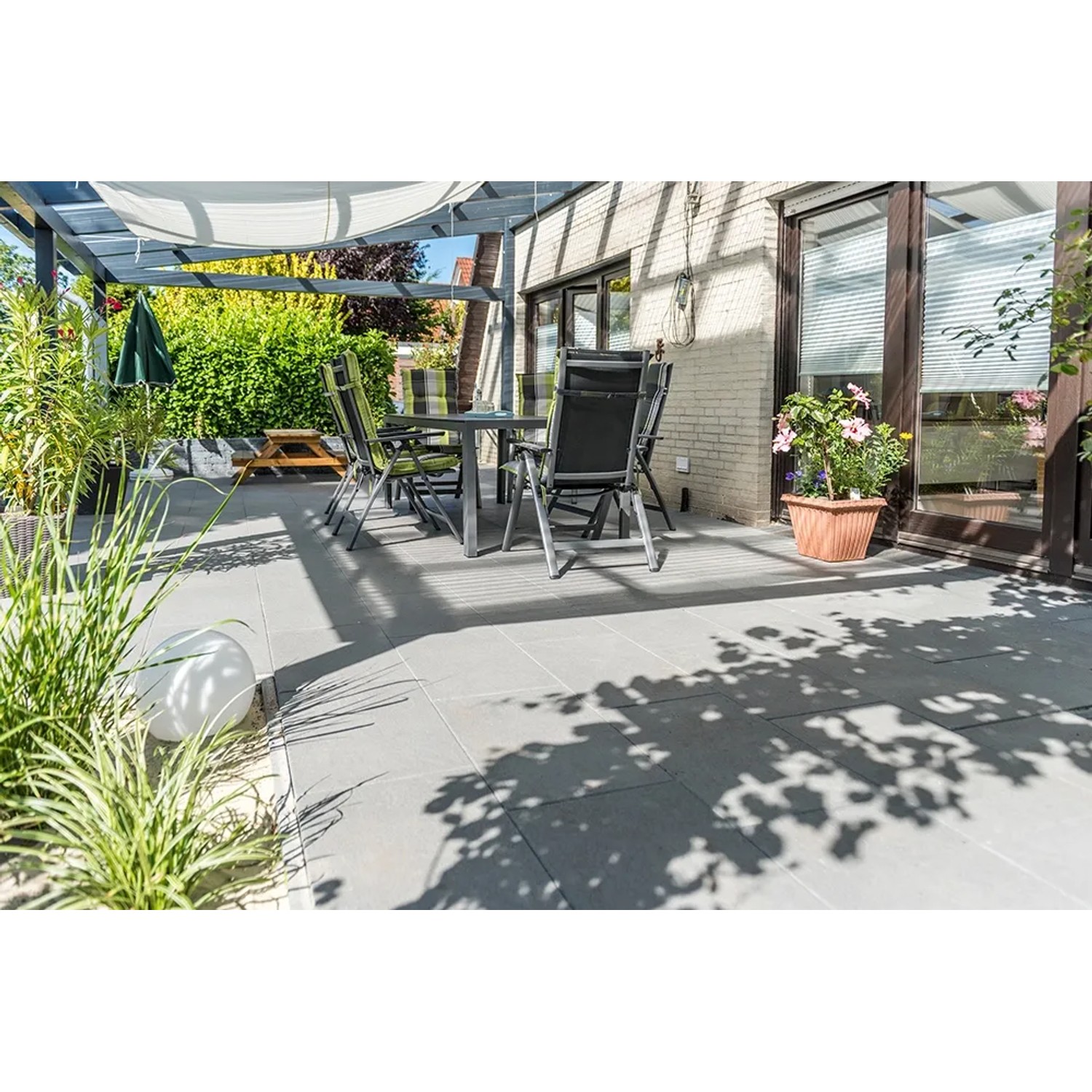 Diephaus Terrassenplatte Rima Basalt, 60x40 cm, auf einer Terrasse mit Gartenmöbeln.