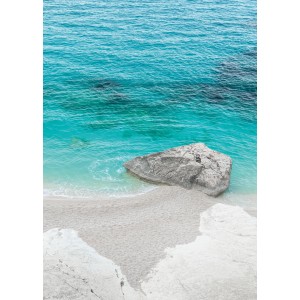 Vlies Fototapete Dreambay: Türkisblaues Meer mit Felsen am Strand.