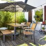 Rechteckiger, brauner Gartentisch Bonlee aus FSC®-Holz mit Sonnenschirmloch und Sitzgelegenheiten.