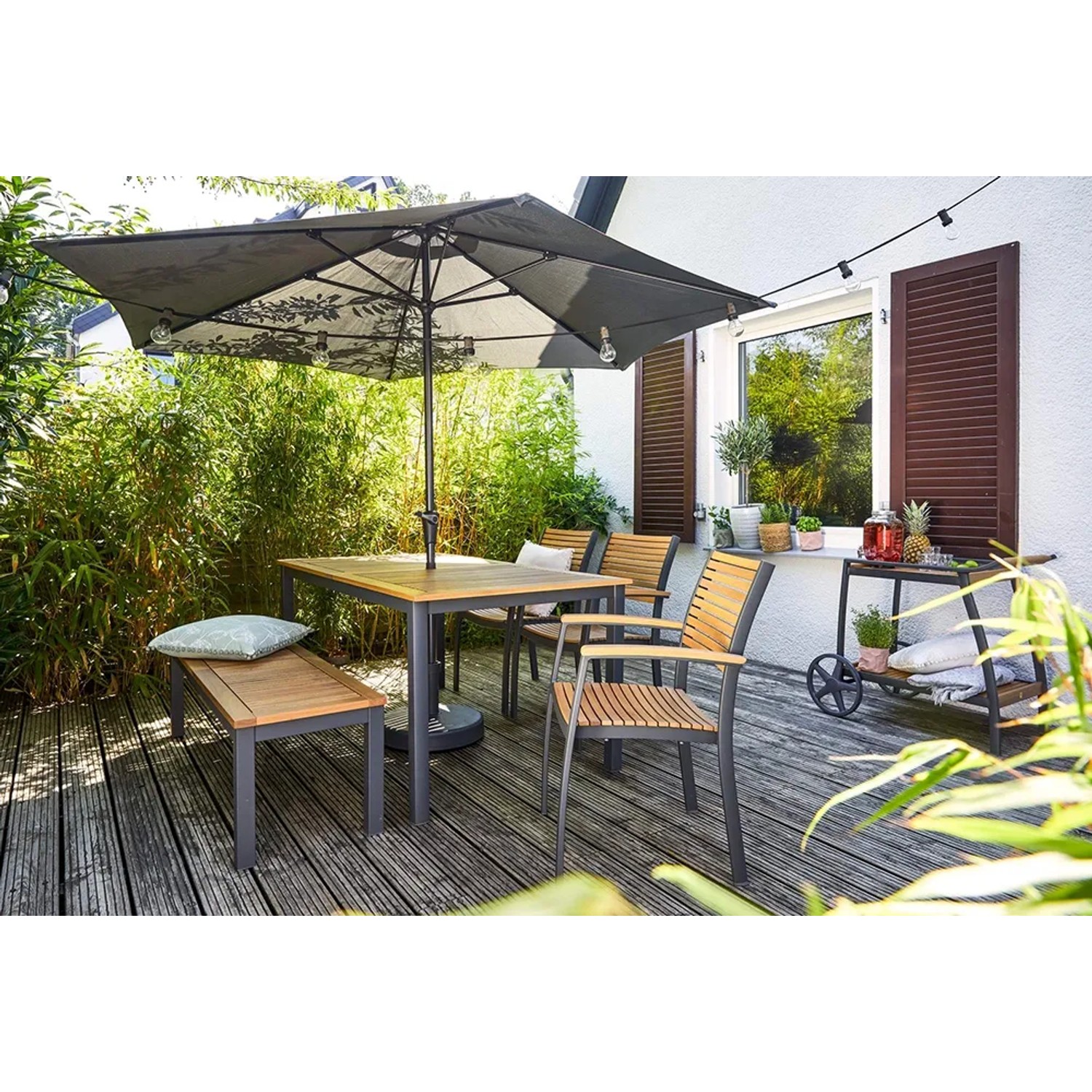 Rechteckiger, brauner Gartentisch Bonlee aus FSC®-Holz mit Sonnenschirmloch und Sitzgelegenheiten.