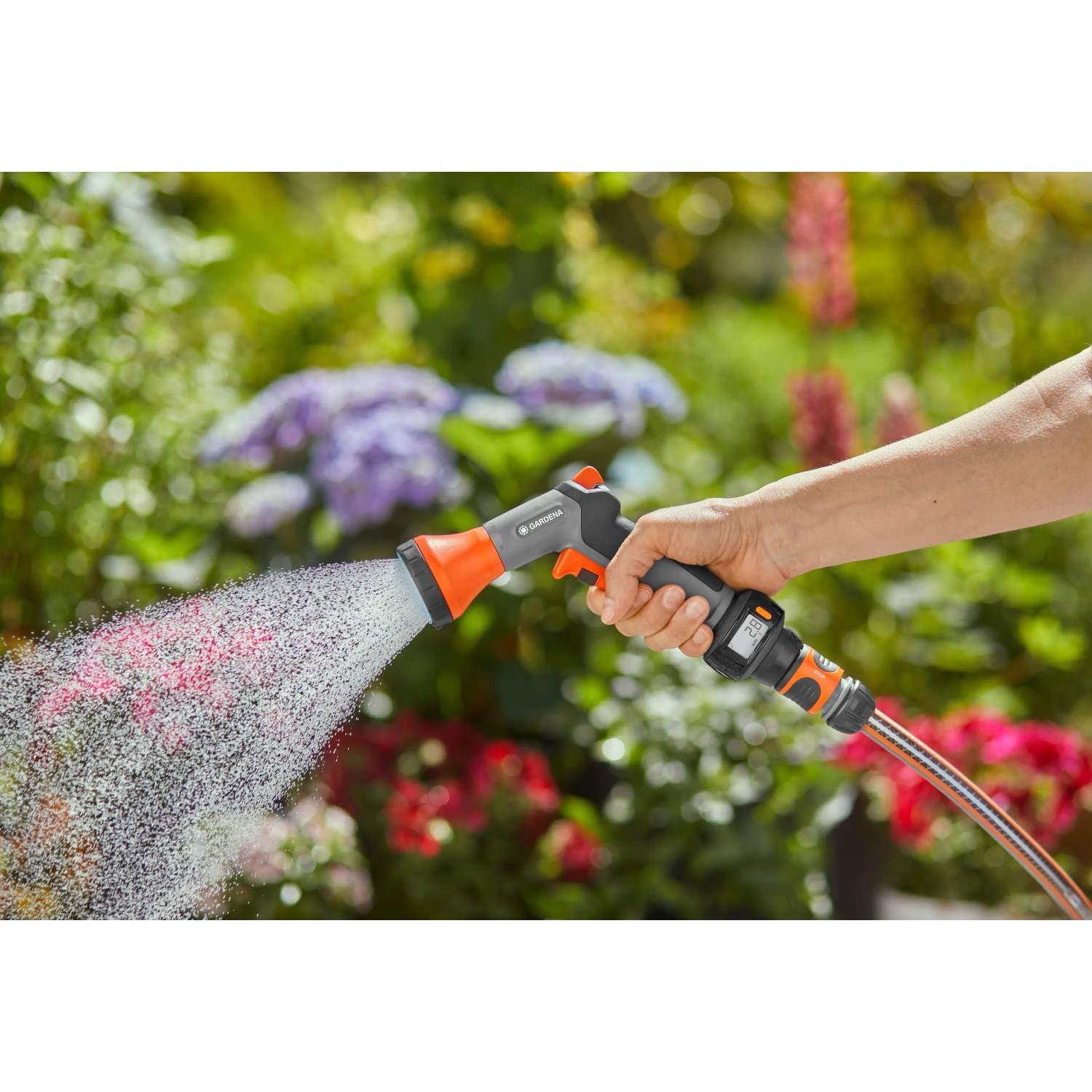 Gardena AquaCount Bewässerungsbrause in Aktion: Hand bewässert Pflanzen mit Brause und digitaler Wasseranzeige.