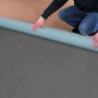 Dachbahn-Rolle wird auf einem Gartenhaus ausgerollt.