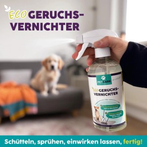 Hand sprüht Hotrega Petcare Eco Geruchsvernichter aus klarer Flasche. Hund auf Sofa im Hintergrund. Neutralisiert Tiergerüche in Räumen.