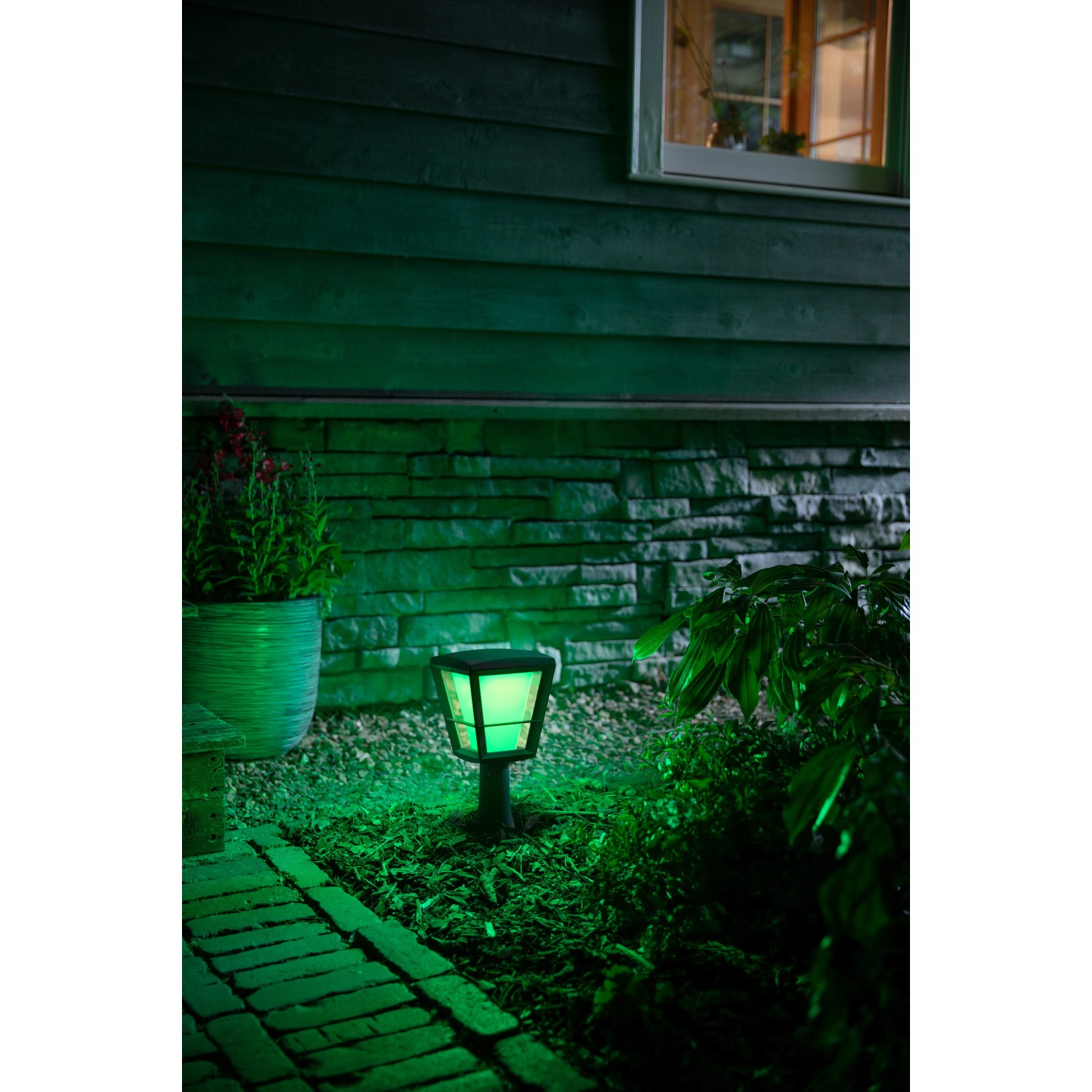 Philips Hue Econic LED-Sockelleuchte im Garten, leuchtet grün. Intelligente Gartenbeleuchtung.