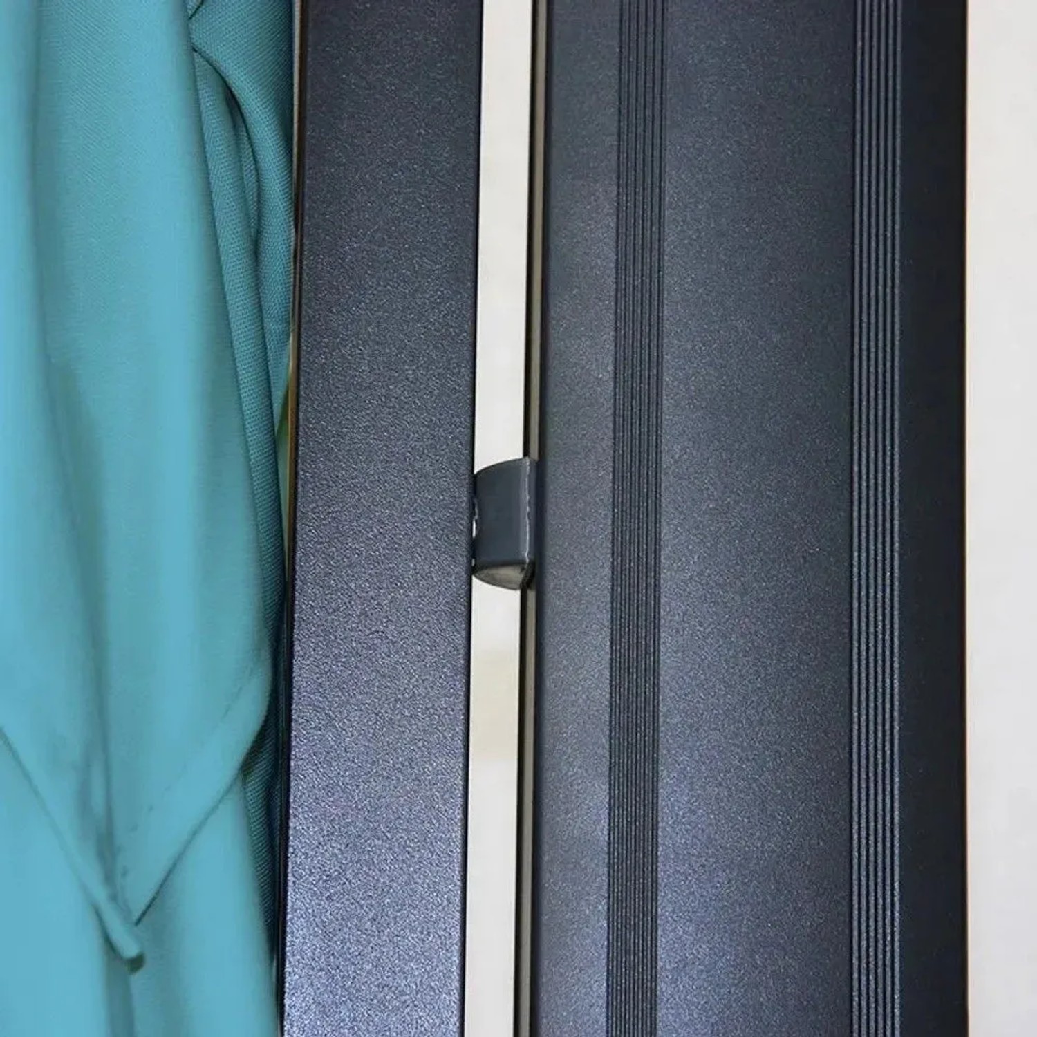 Nahaufnahme des türkisen Ampelschirmbezugs und des dunklen Aluminiumgestänges. Detail des robusten Sonnenschirm-Rahmens.
