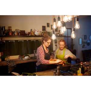 Zwei Frauen kochen unter Philips E27 LED Lampen in Glühlampenform in einer Küche.