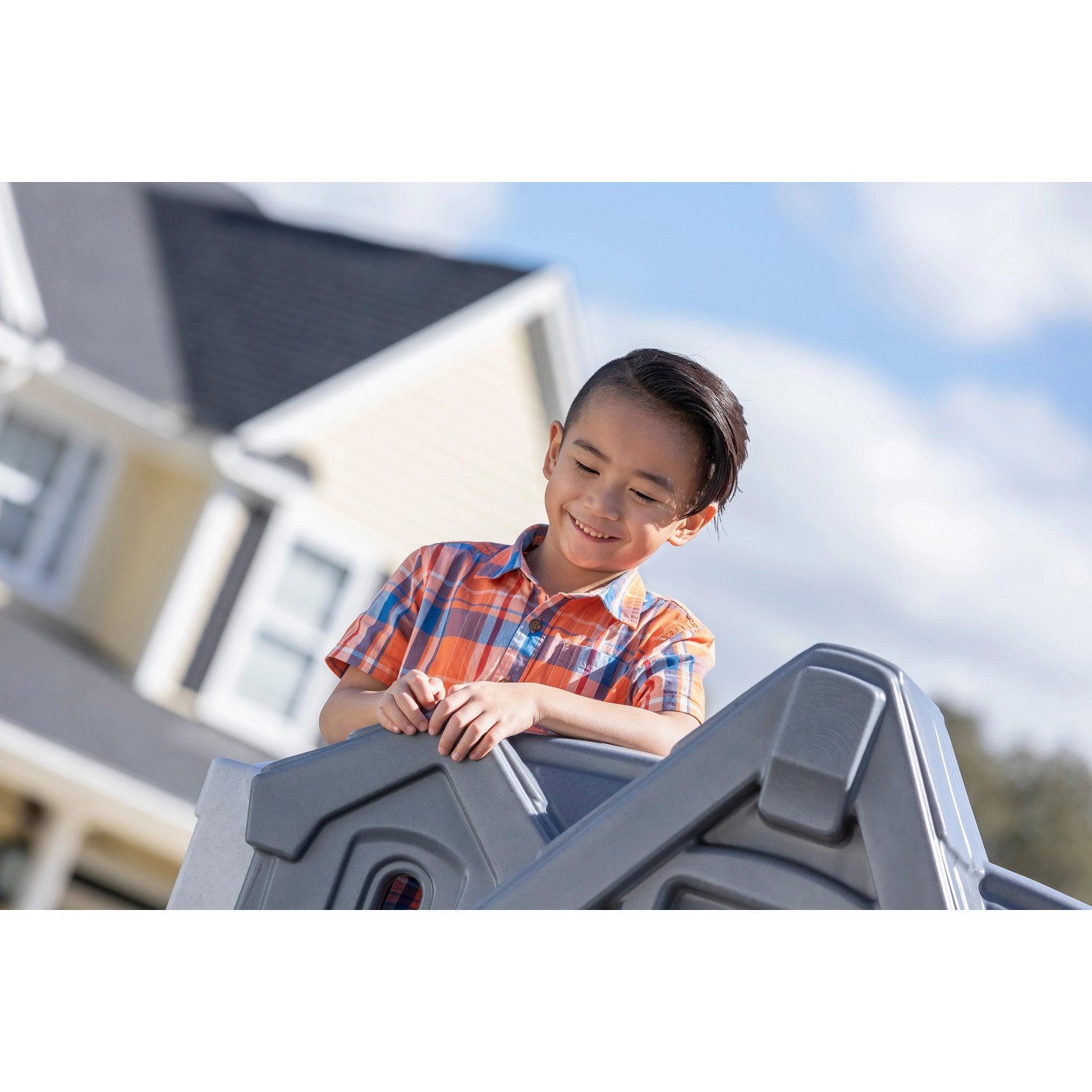 Kind spielt im Step2 Spielhaus Adventures mit Rutsche im Garten.