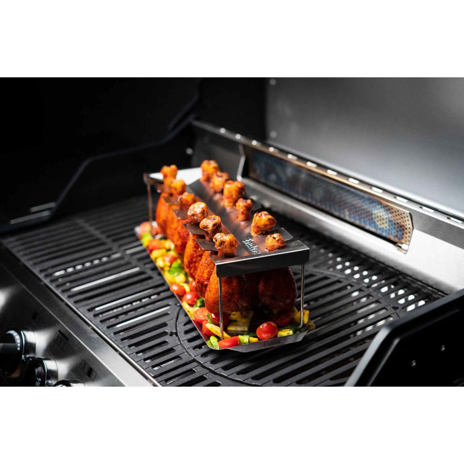 Enders Chicken Wing Halter aus Edelstahl mit Hähnchenflügeln und Gemüse auf einem Grill.