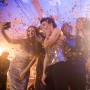 Freundinnen feiern mit goldenem Konfetti und Party Poppern, eine macht ein Selfie.