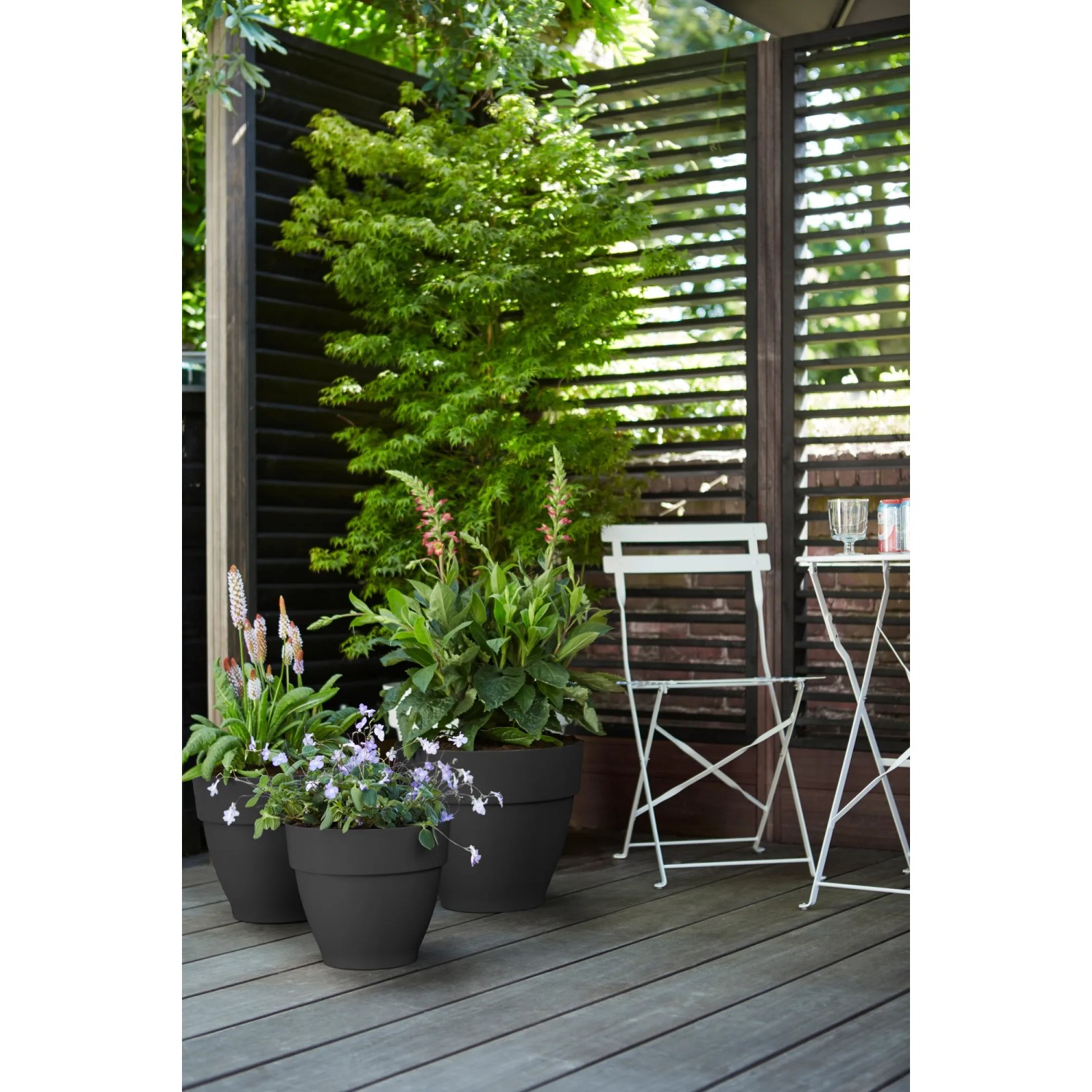 Elho Blumentöpfe Vibia Campana, Ø 20cm, Anthrazit, mit Pflanzen auf einer Terrasse.