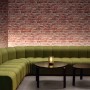 Wohnraum mit roter Marburg Vliestapete GZSZ in 3D Steinoptik hinter grüner Couch und Tisch.