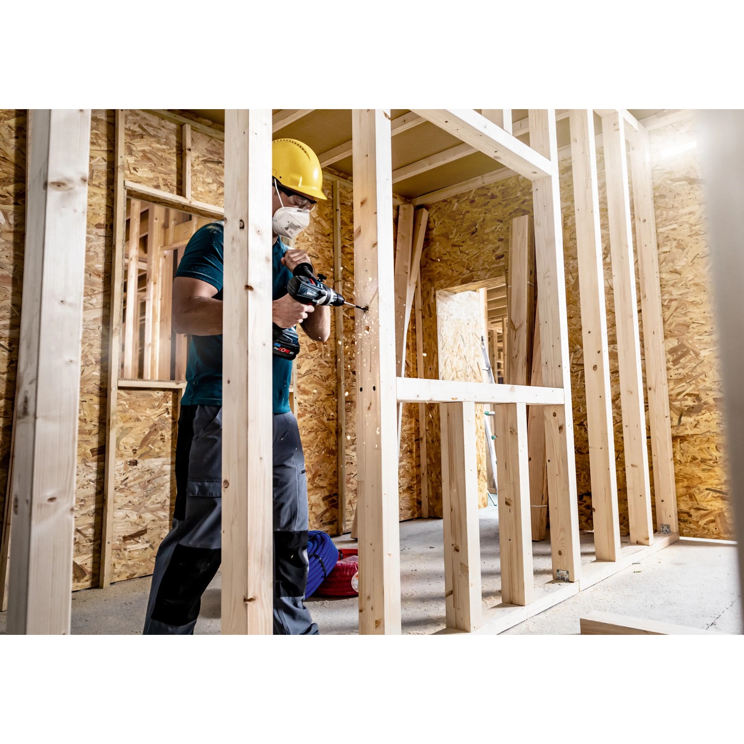 Handwerker bohrt mit Bosch Expert Flachfräsbohrer Löcher in Holzkonstruktion.