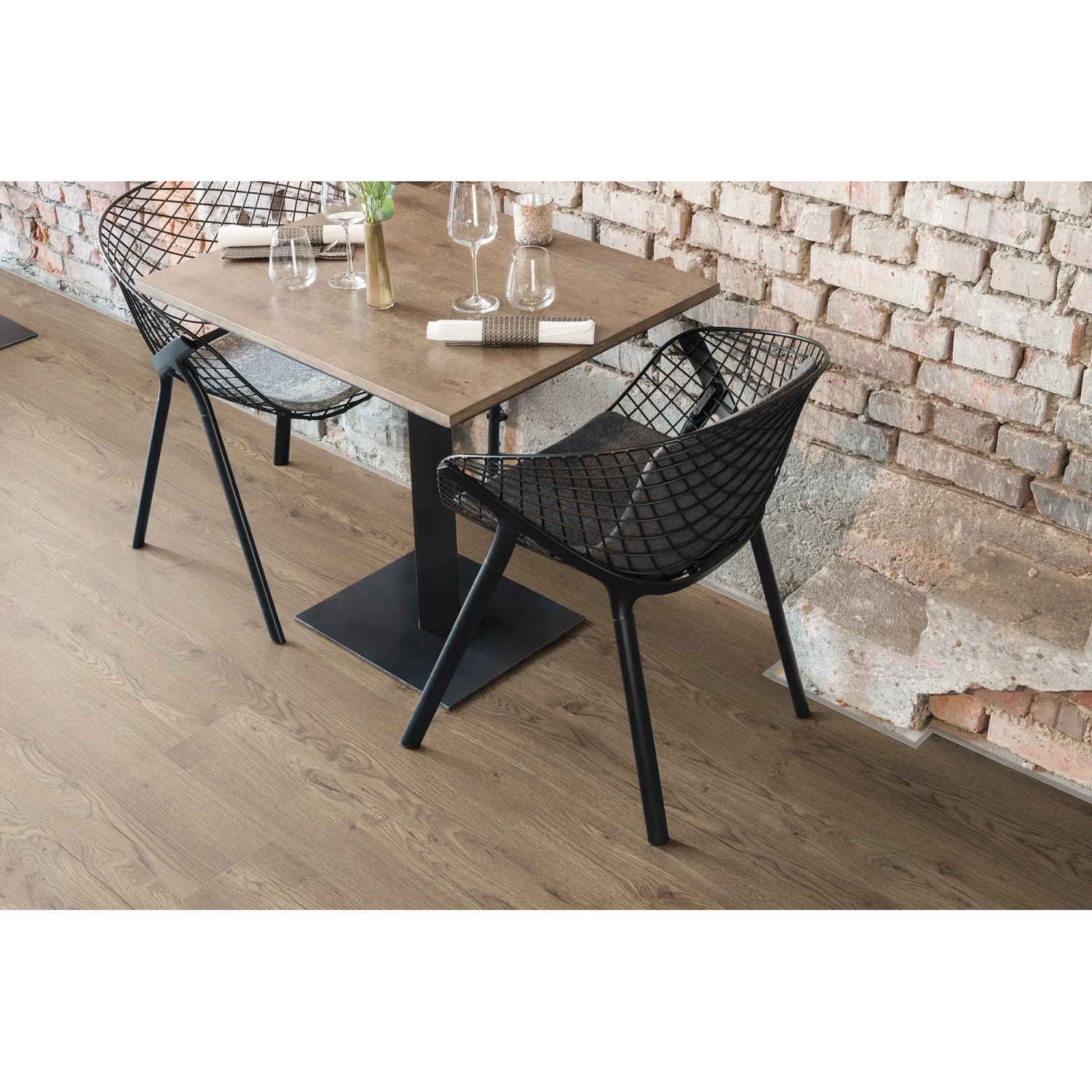 Egger NatureSense Aqua Laminat in Braun verlegt unter Tisch mit Stühlen vor Backsteinwand.