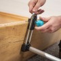 Hände befestigen wolfcraft Türfutterstrebe Easy an Holz-Türrahmen. Spannwerkzeug zur Montage und Ausrichtung der Zarge.