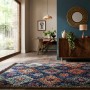 Dunkelblauer Flair Rugs Jakob Shaggy Hochflorteppich mit bunten Rautenmustern und Quasten, auf Holzboden im Wohnzimmer.