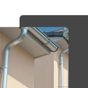 Silbernes Zambelli Fallrohr aus Zink, DN 100, an heller Hauswand. Dachentwässerung mit passender Dachrinne.