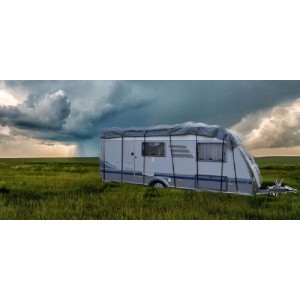 Graues GreenYard® Wohnwagen Schutzdach 500 cm auf einer Wiese vor dunklen Wolken.
