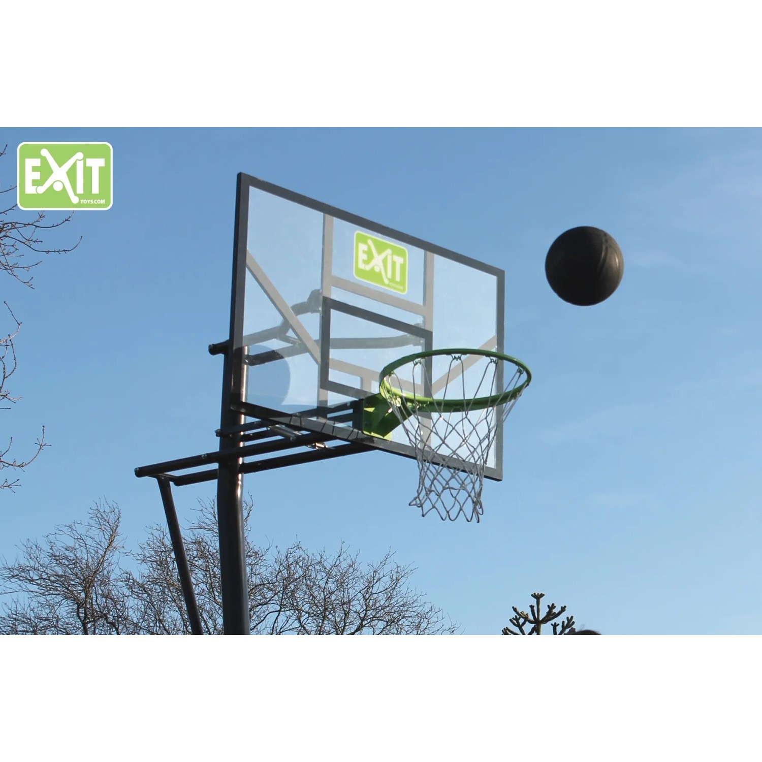 EXIT Galaxy Basketballkorb, grün/schwarz, zur Bodenmontage mit Ball vor blauem Himmel.